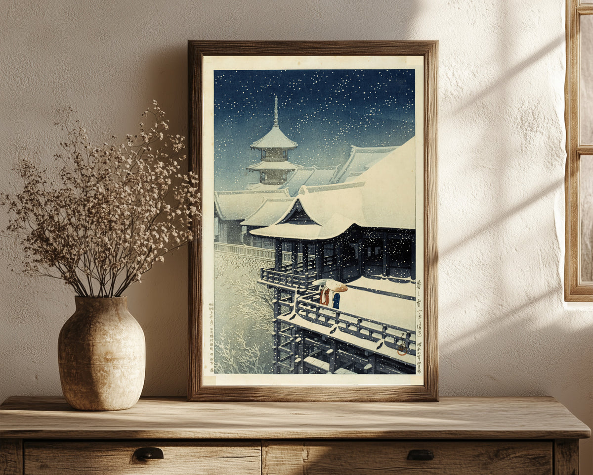 Framed art print of Spring Snow at Kiyomizu Temple, Kyoto by Kawase Hasui, in a dark wood frame leaning on a rustic console beside dried flowers