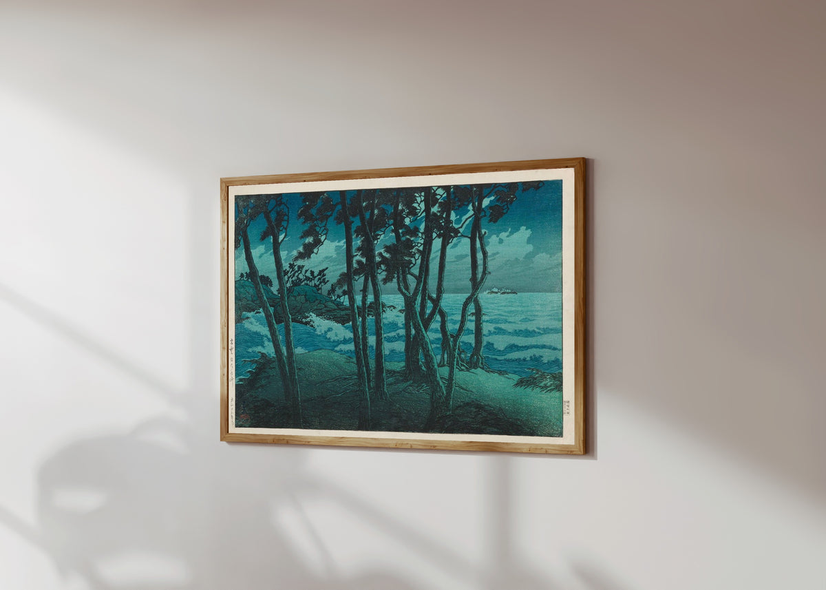 Framed art print of Izumo Seafront by Kawase Hasui, in a light wood frame on a sunlit white wall, seen at a slight angle