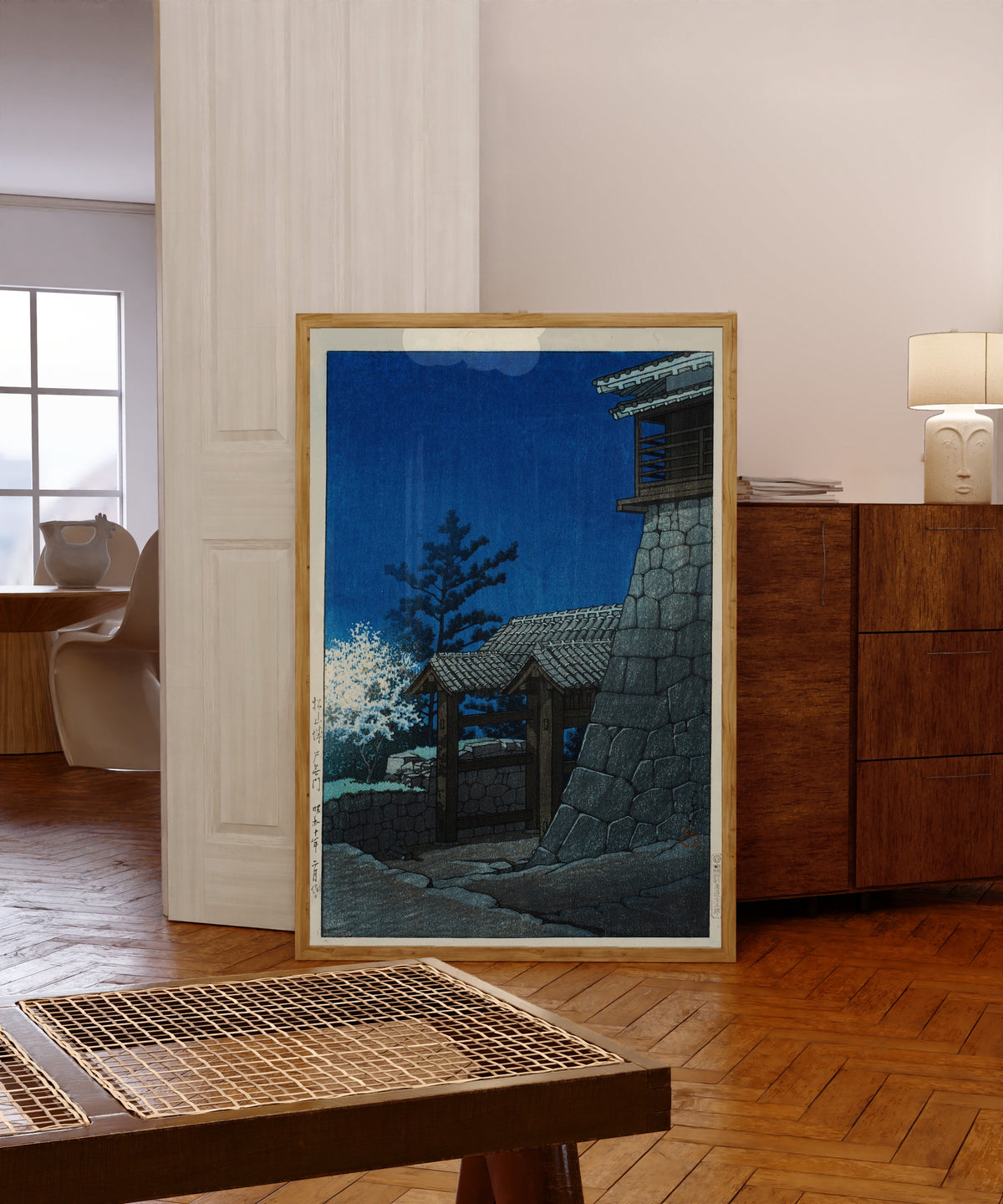 Framed art print of Tonashi Gate, Matsuyama Castle by Kawase Hasui, in a light wood frame leaning in a warm room with a parquet floor