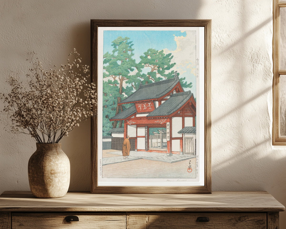 Framed art print of Zuisen Temple, Narumi by Kawase Hasui, in a dark wood frame leaning on a rustic console beside dried flowers