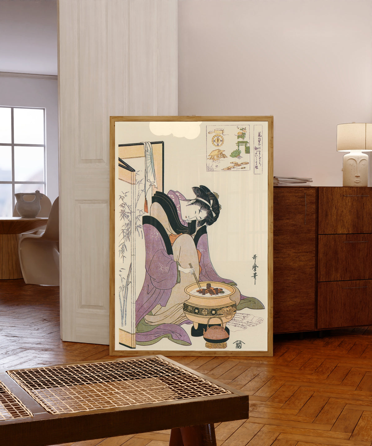 Framed art print of Okita of Naniwaya, before a Brazier by Kitagawa Utamaro, in a light wood frame leaning in a warm room with a parquet floor