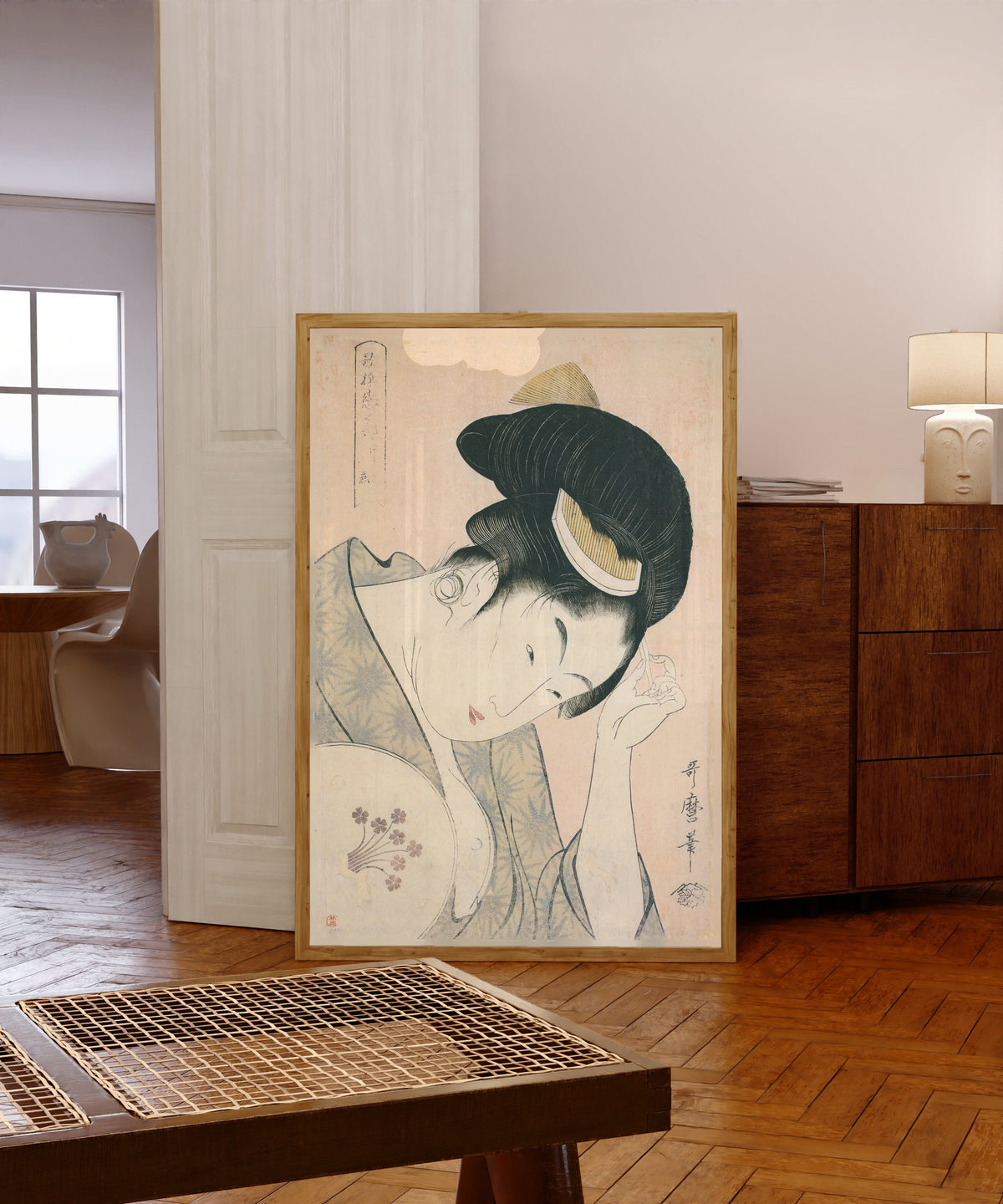 Framed art print of Revealed Love, from Anthology of Poems: The Love… by Kitagawa Utamaro, in a light wood frame leaning in a warm room with a parquet floor