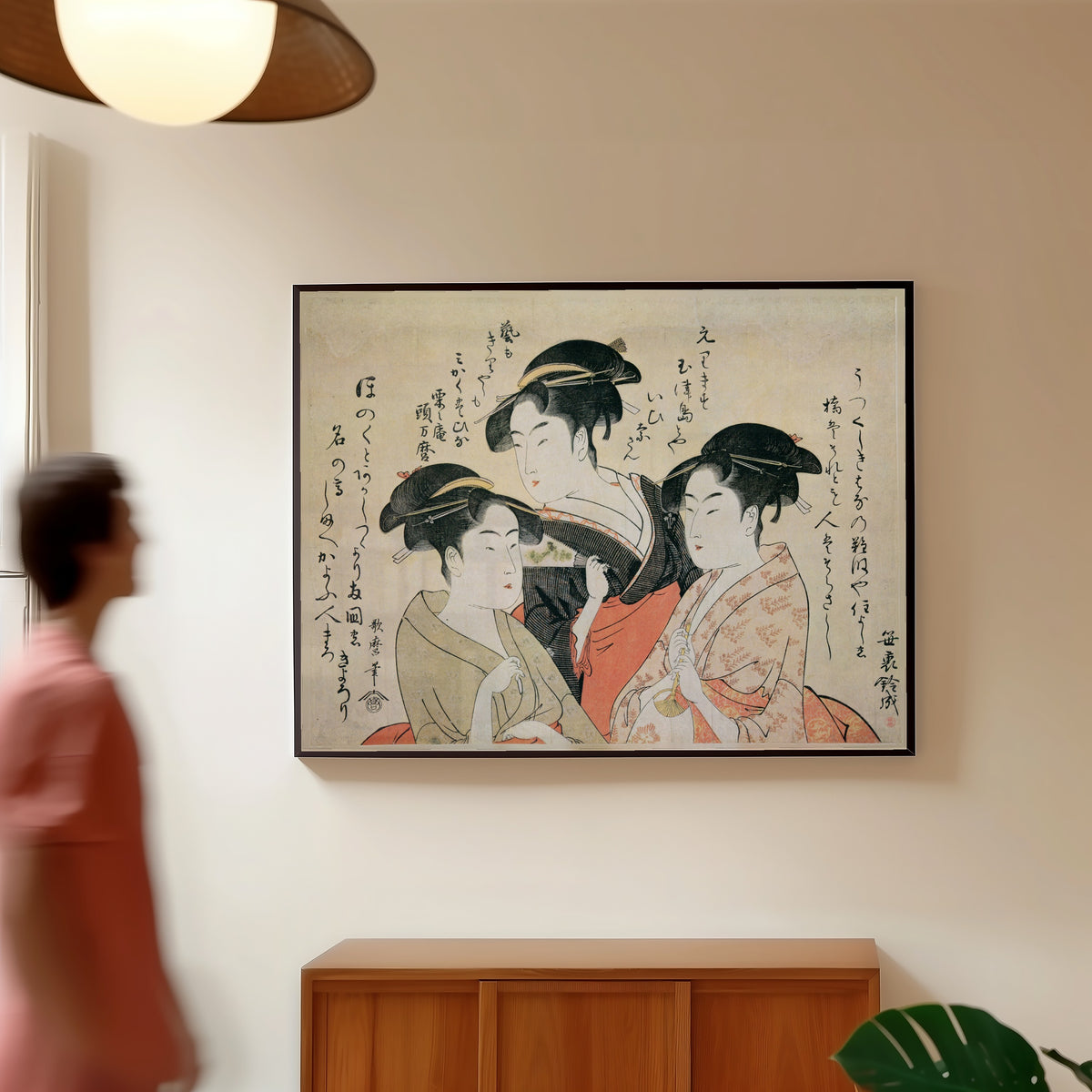 Framed art print of Three Beauties of the Present Day: Okita, Toyohina, Ohisa by Kitagawa Utamaro, in a slim black frame on a warm wall in a sunlit room