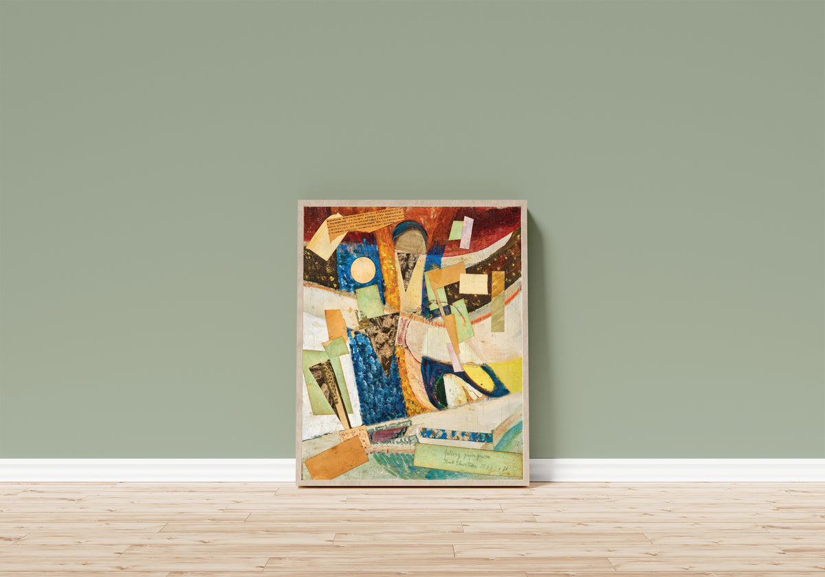 Framed art print of c 71 falling paper pieces by Kurt Schwitters, in a light wood frame leaning on a sage green wall above a wooden floor