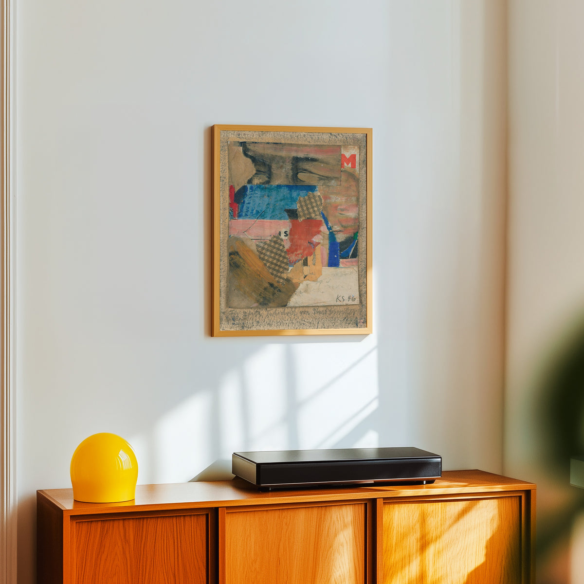Framed art print of Für Edith Tschichold by Kurt Schwitters, in a light wood frame on a white wall above an orange sideboard