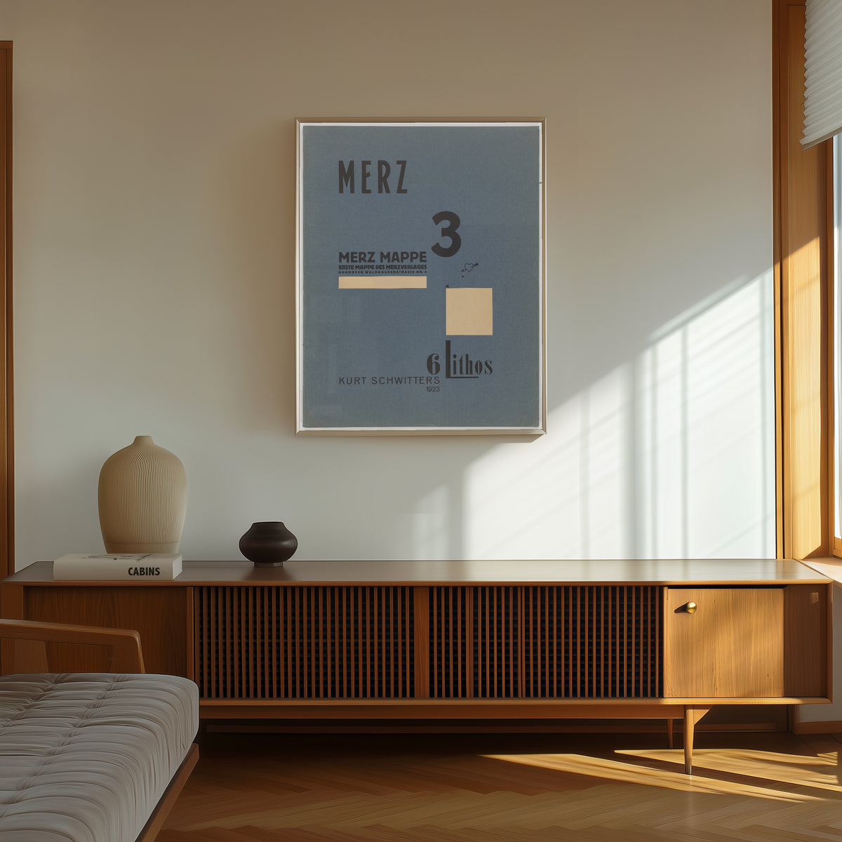Framed art print of Merz 3. Kurt Schwitters 6 Lithos Pl.1 by Kurt Schwitters, in a thin light frame on a sunlit wall above a wooden sideboard
