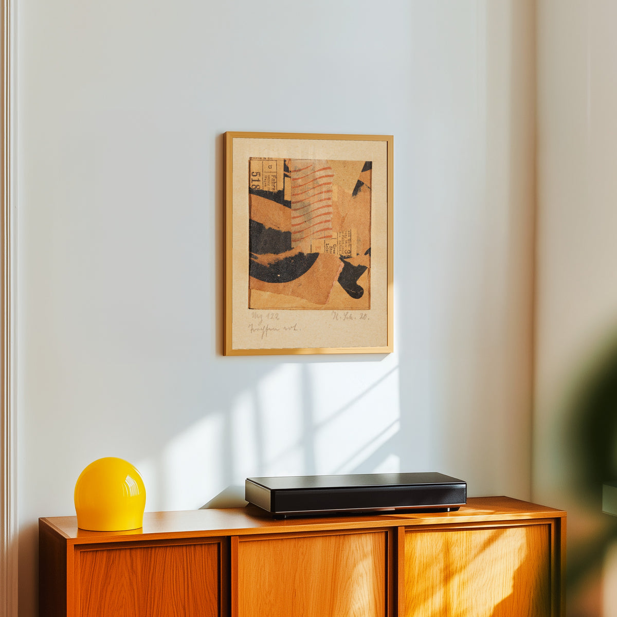 Framed art print of Mz 122 Tropfen rot. (Merzzeichnung) by Kurt Schwitters, in a light wood frame on a white wall above an orange sideboard