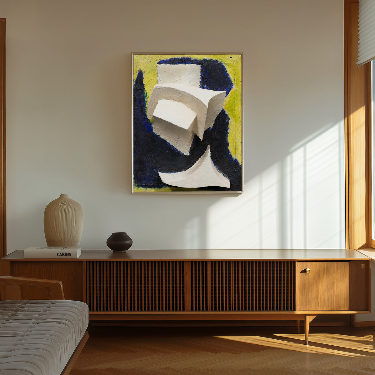 Framed art print of Ohne Titel (Bewegtes Weiss auf Blau und Gelb) by Kurt Schwitters, in a thin light frame on a sunlit wall above a wooden sideboard