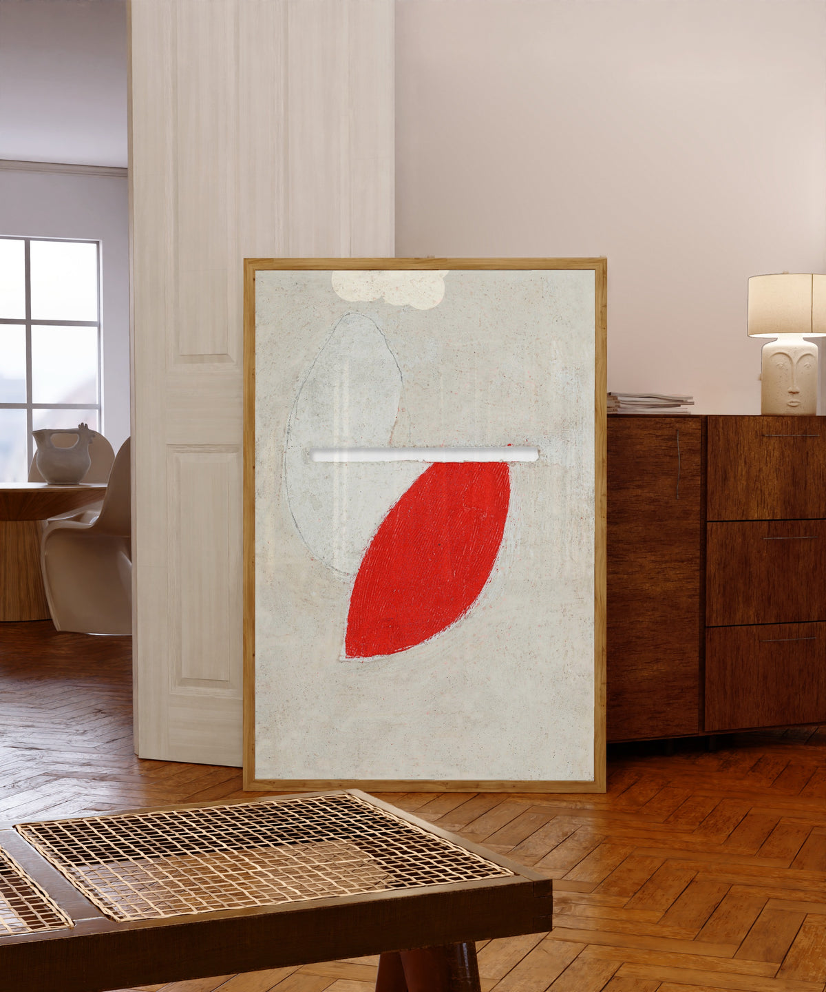 Framed art print of Ohne Titel (Mit Schlitz) by Kurt Schwitters, in a light wood frame leaning in a warm room with a parquet floor