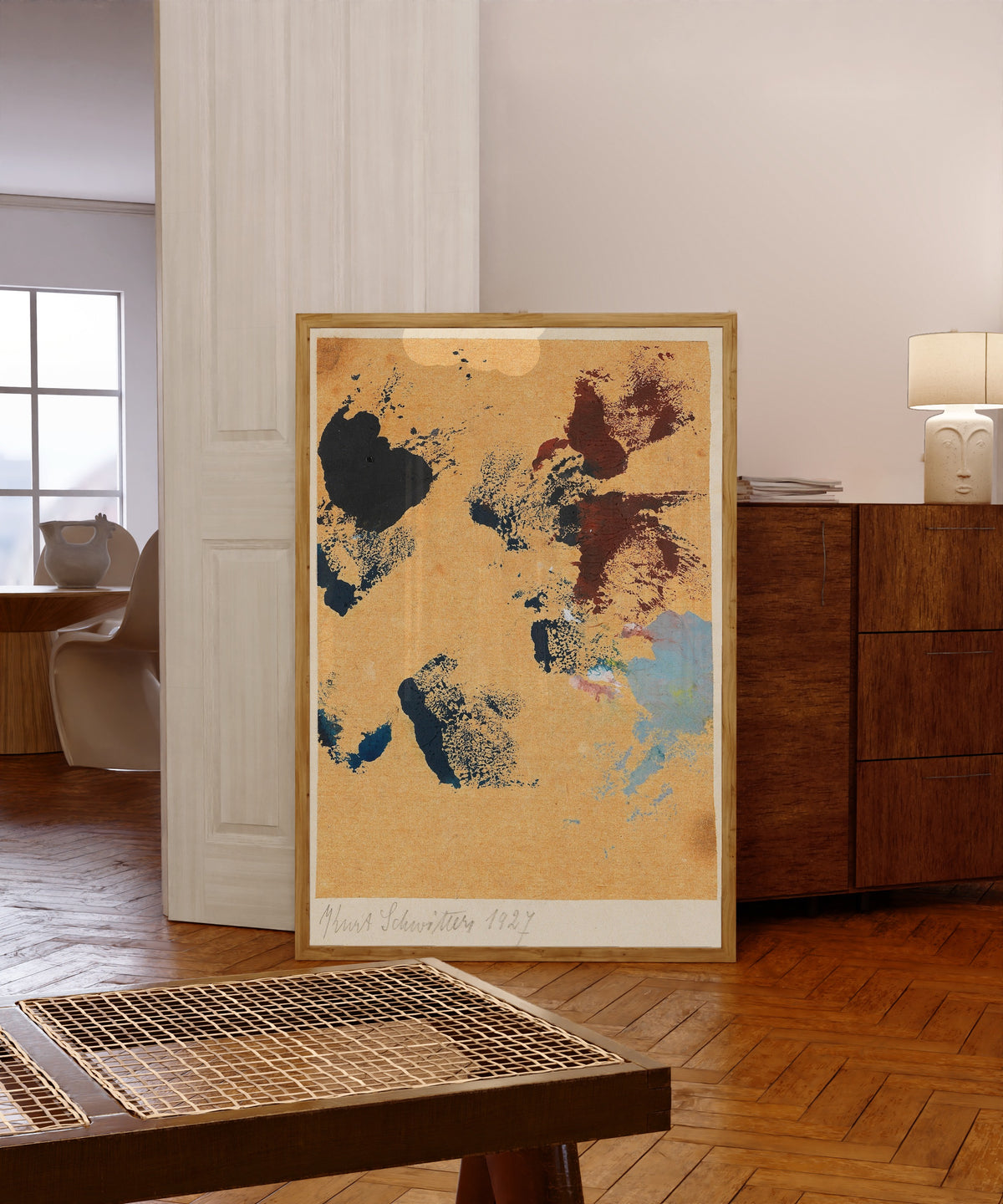 Framed art print of Ohne Titel (Spritzen Farbe) by Kurt Schwitters, in a light wood frame leaning in a warm room with a parquet floor