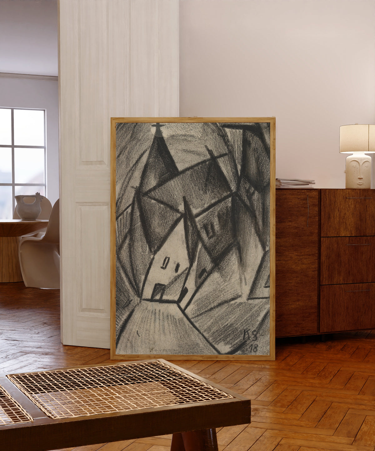 Framed art print of Z31 Nächtliches Dorf by Kurt Schwitters, in a light wood frame leaning in a warm room with a parquet floor