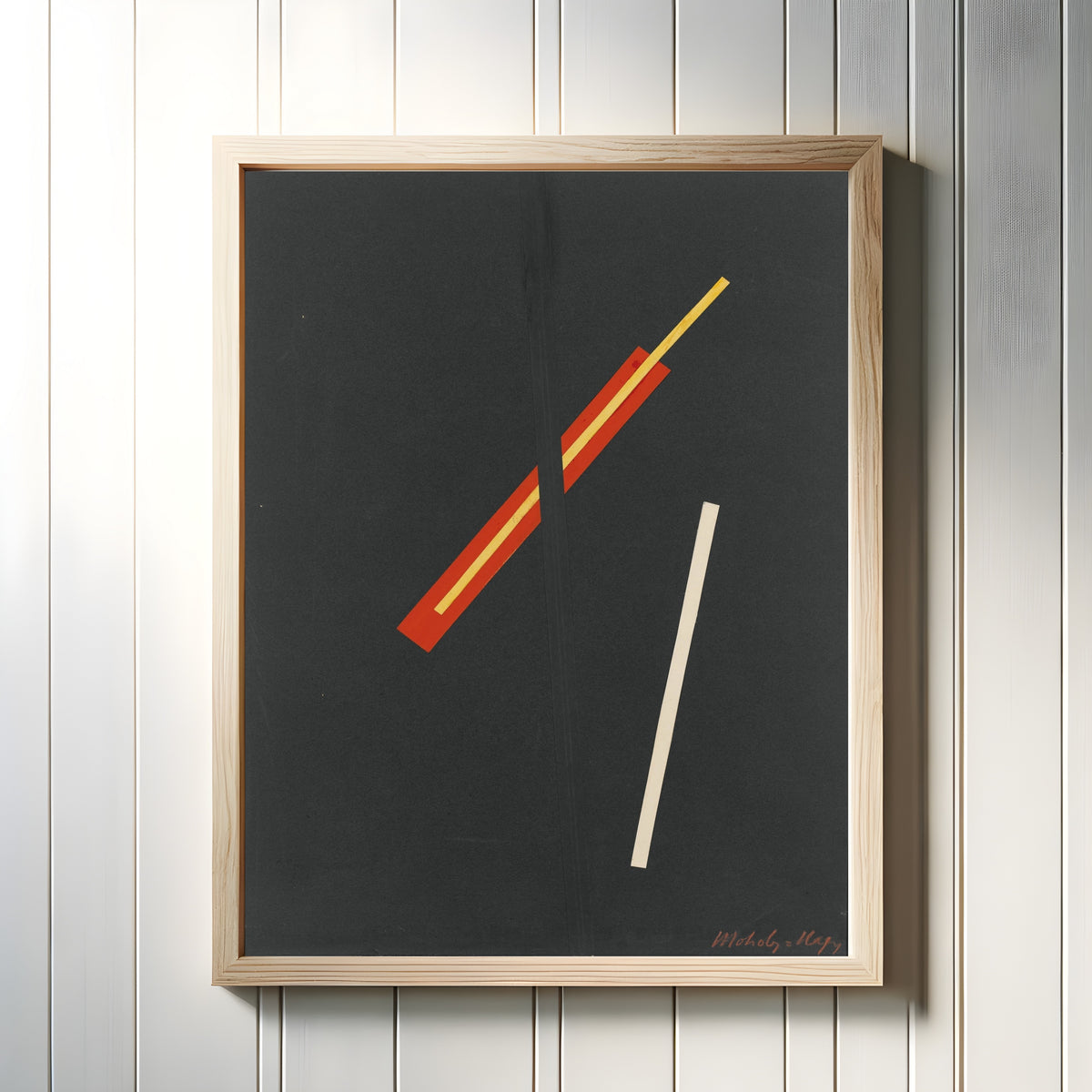 Framed art print of Collage with Three Elements by László Moholy-Nagy, in a light wood frame on a white panelled wall
