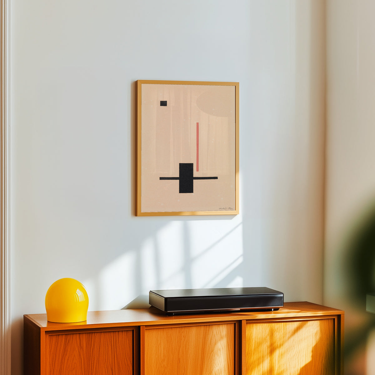 Framed art print of Composition by László Moholy-Nagy, in a light wood frame on a white wall above an orange sideboard