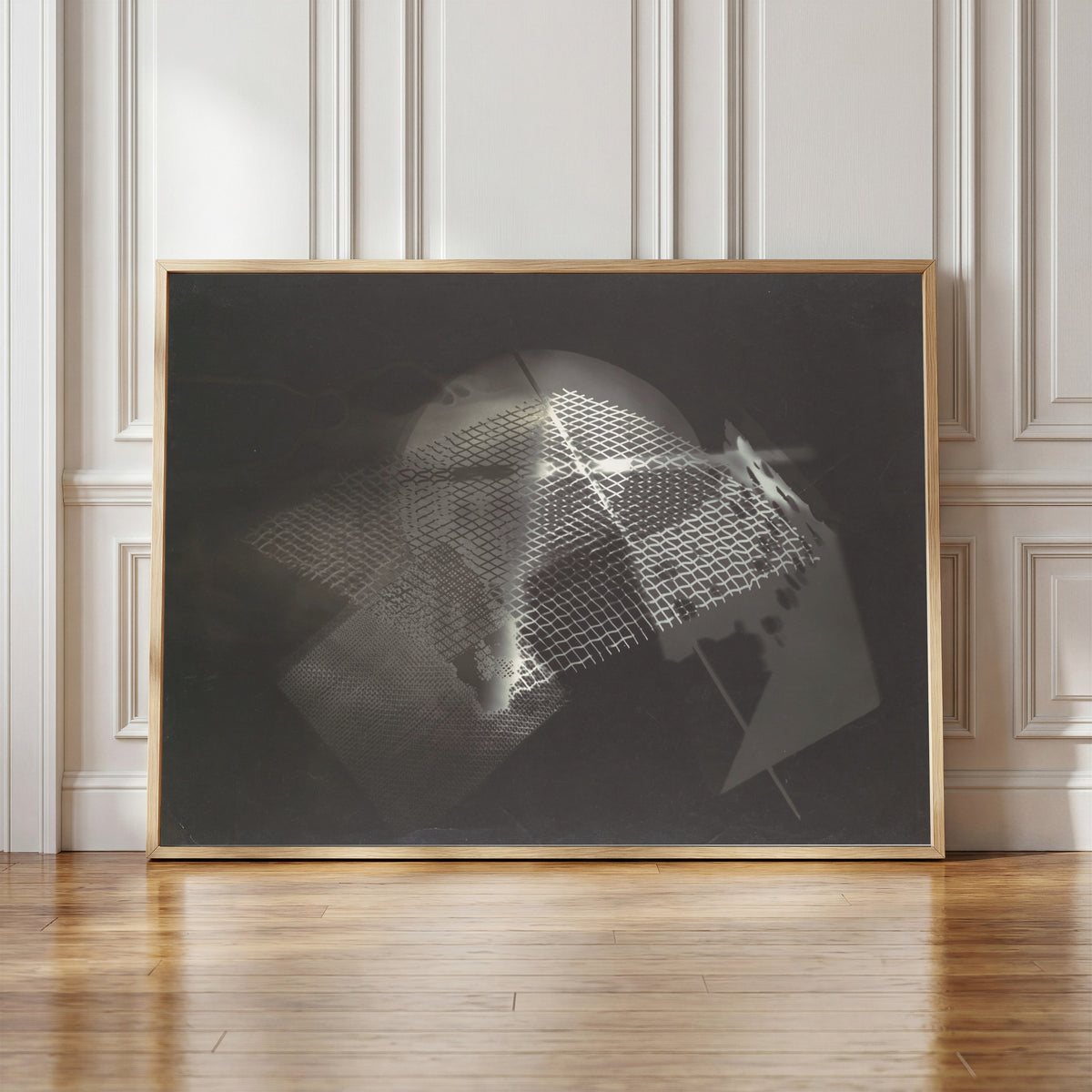 Framed art print of Fotogramm (1922) by László Moholy-Nagy, in a light wood frame leaning against a panelled white wall