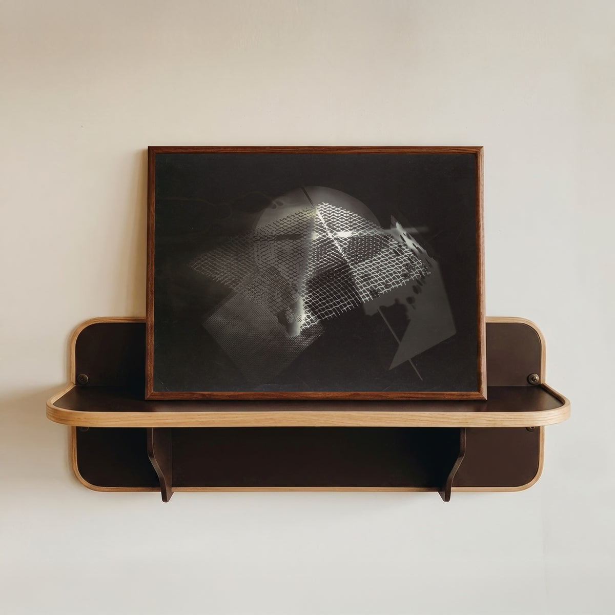 Framed art print of Fotogramm (1922) by László Moholy-Nagy, in a dark wood frame resting on a wall shelf