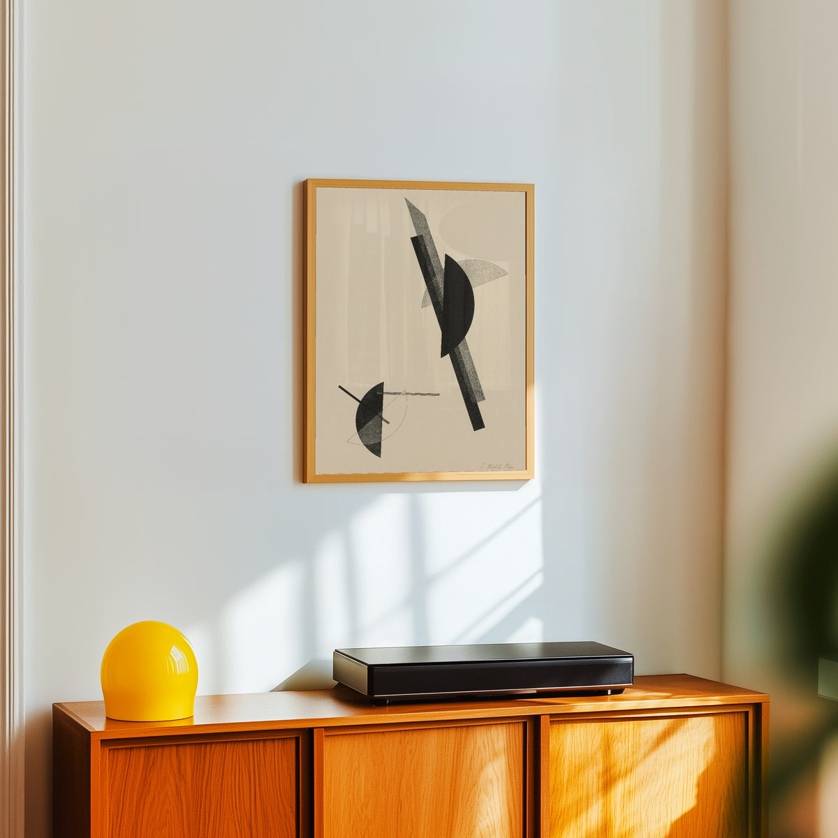 Framed art print of Kestnermappe, Komposition by László Moholy-Nagy, in a light wood frame on a white wall above an orange sideboard