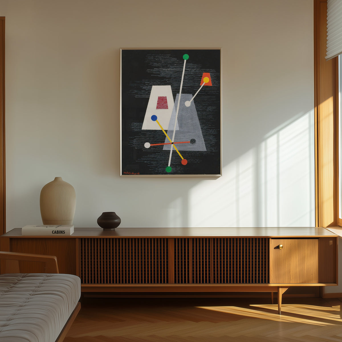 Framed art print of Truncated Pyramids by László Moholy-Nagy, in a thin light frame on a sunlit wall above a wooden sideboard