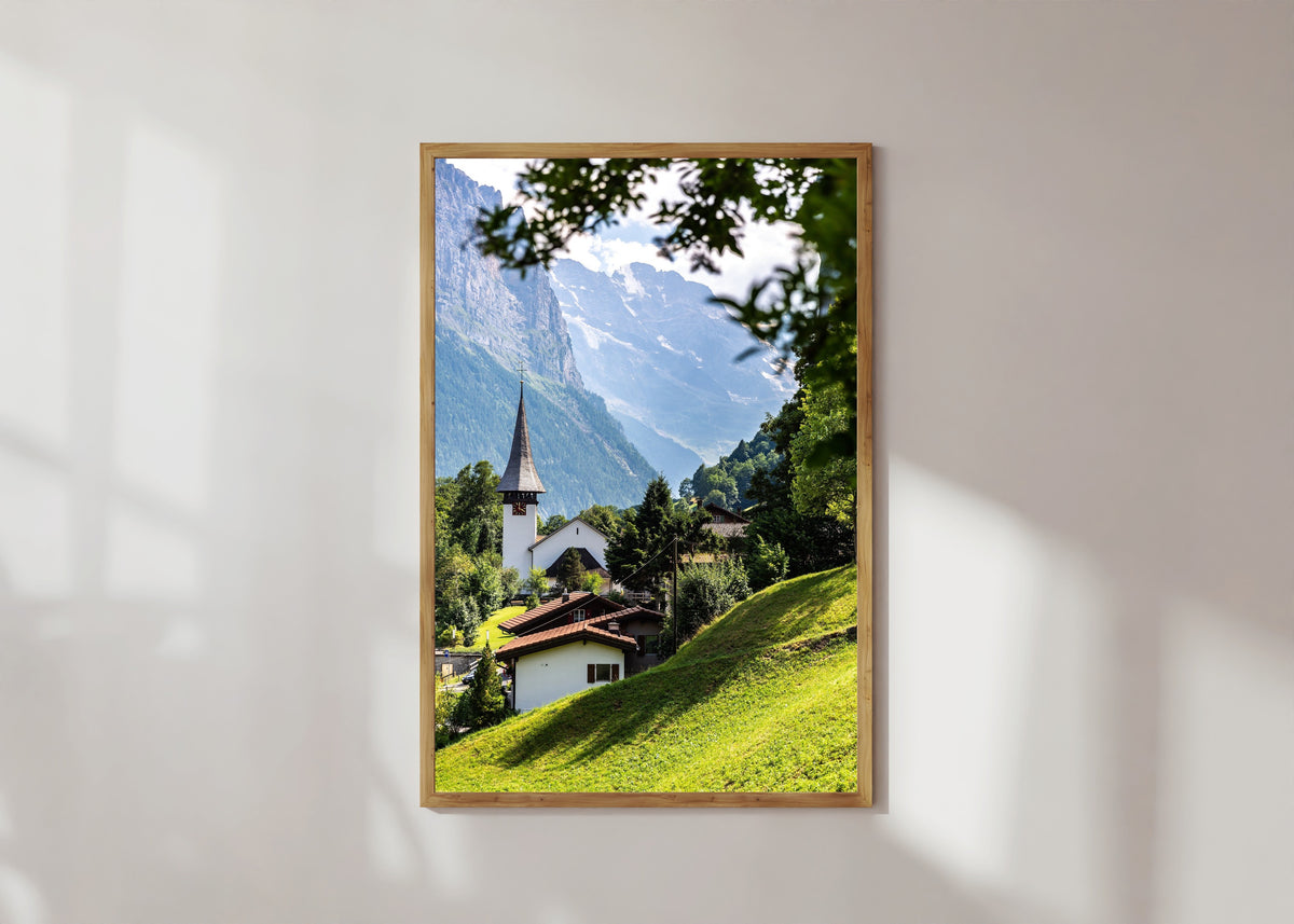 Framed art print of Lauterbrunnen by Daniela Faust, in a light wood frame on a sunlit white wall