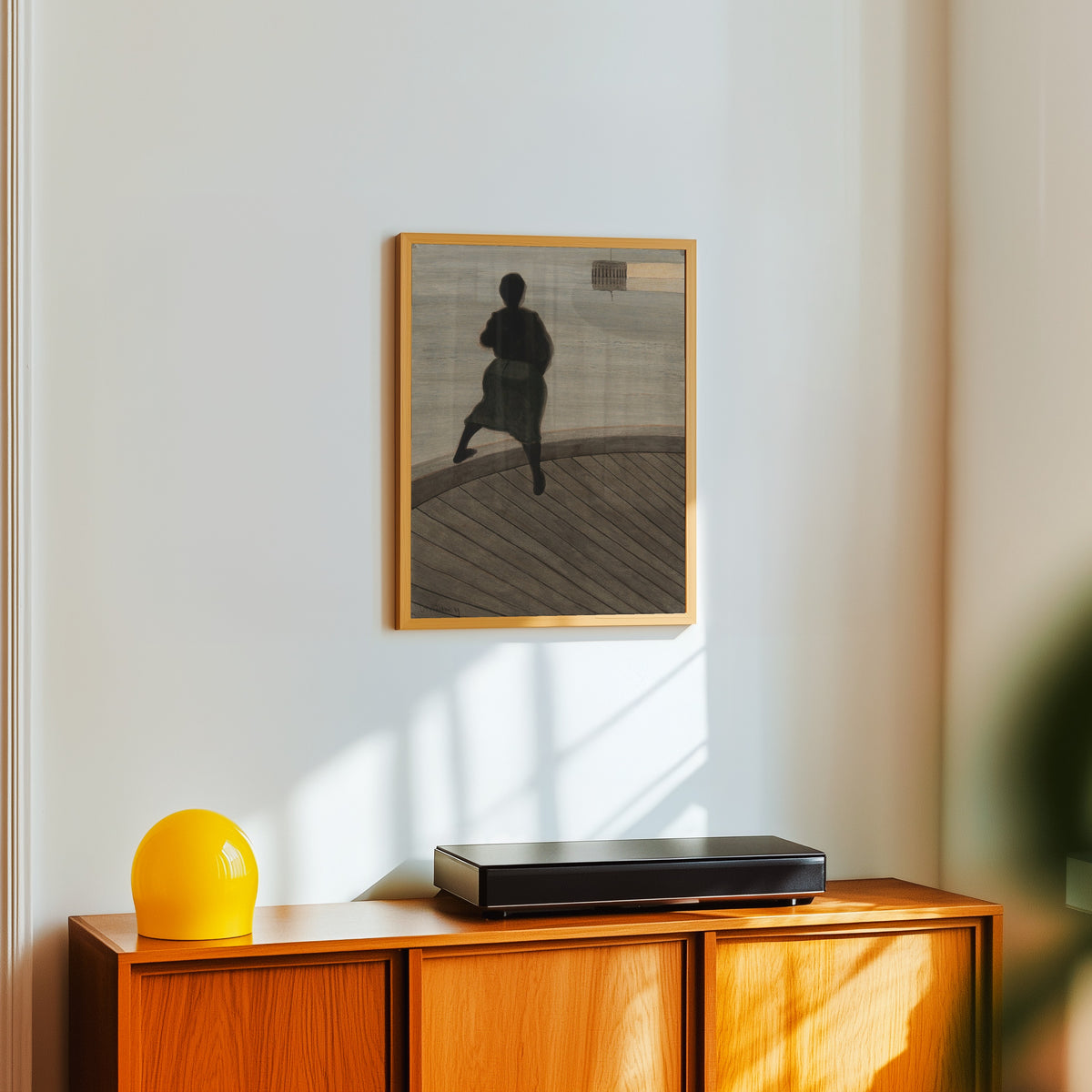 Framed art print of Femme de pêcheur sur le ponton by Léon Spilliaert, in a light wood frame on a white wall above an orange sideboard
