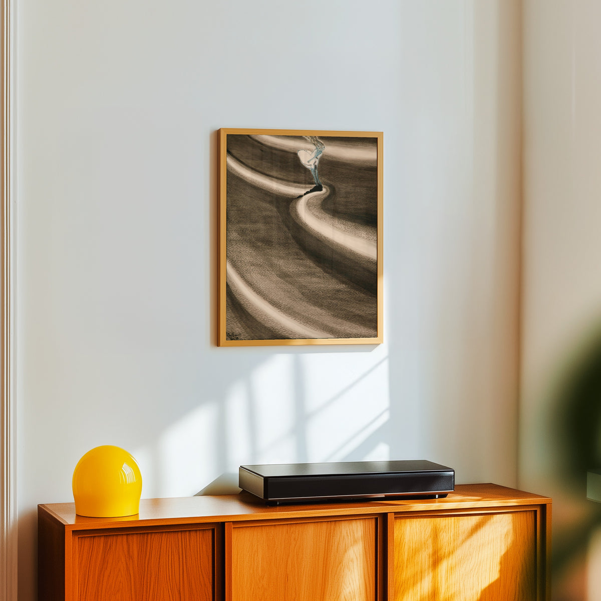 Framed art print of Fillettes devant la vague by Léon Spilliaert, in a light wood frame on a white wall above an orange sideboard