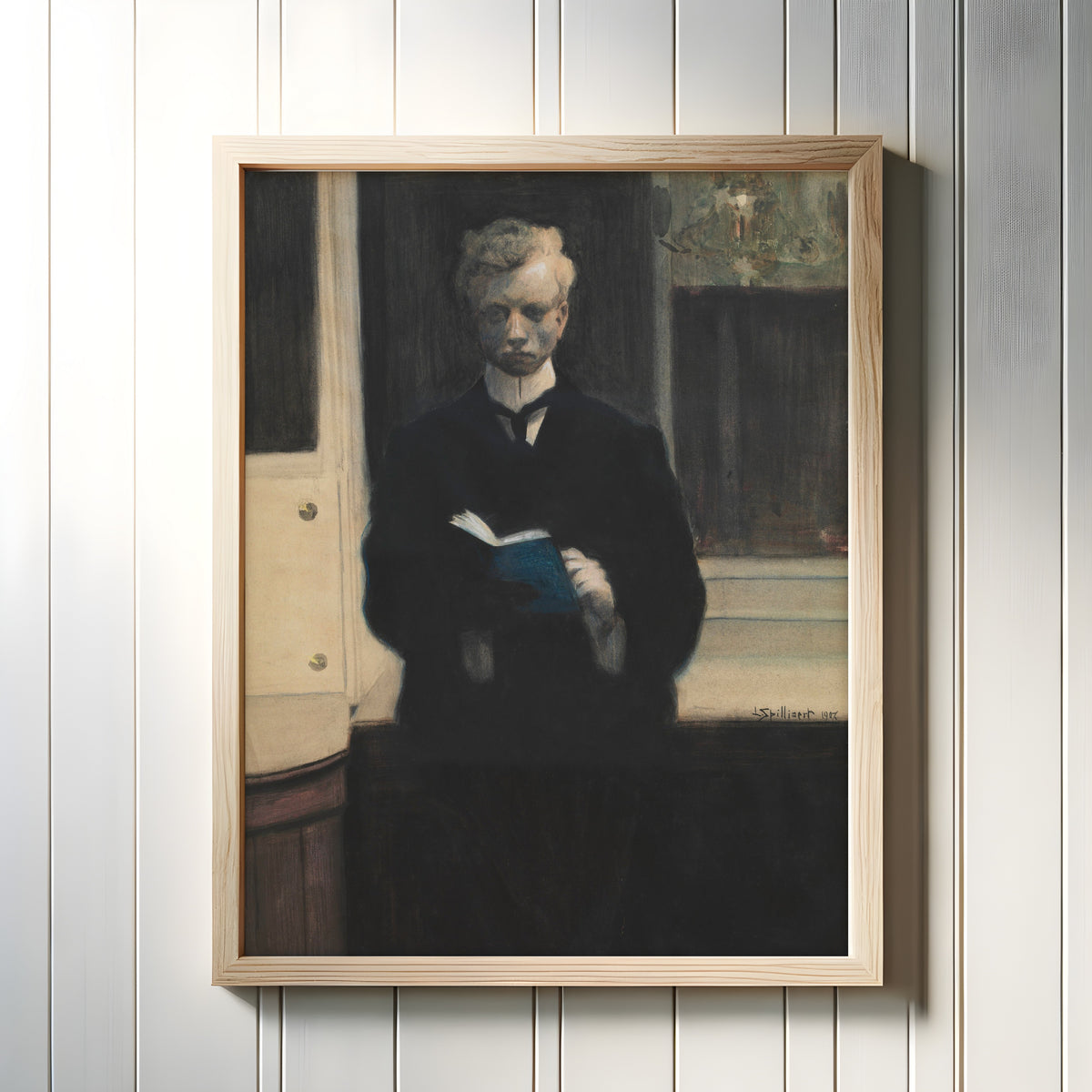Framed art print of Self-Portrait with Blue Sketchbook by Léon Spilliaert, in a light wood frame on a white panelled wall