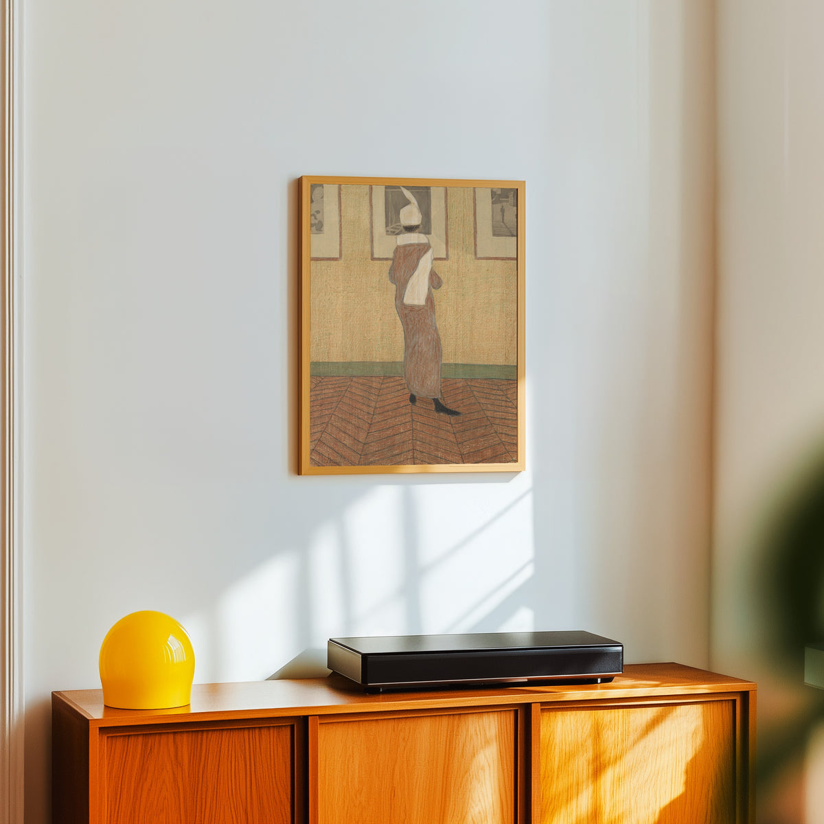 Framed art print of Woman at an Exhibition by Léon Spilliaert, in a light wood frame on a white wall above an orange sideboard