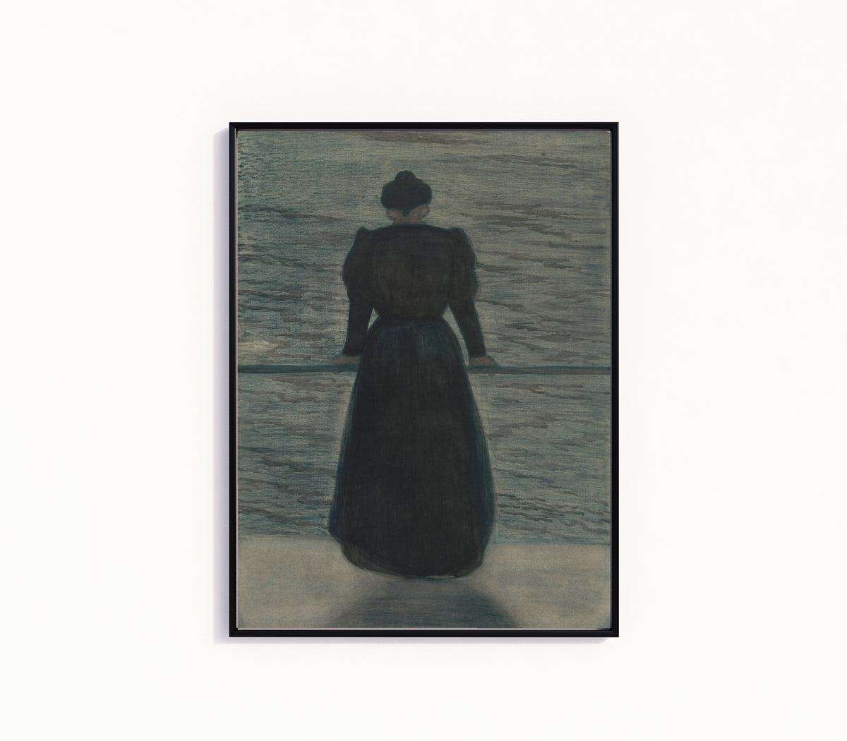 Framed art print of Woman by the Sea by Léon Spilliaert, in a slim black frame on a plain white wall