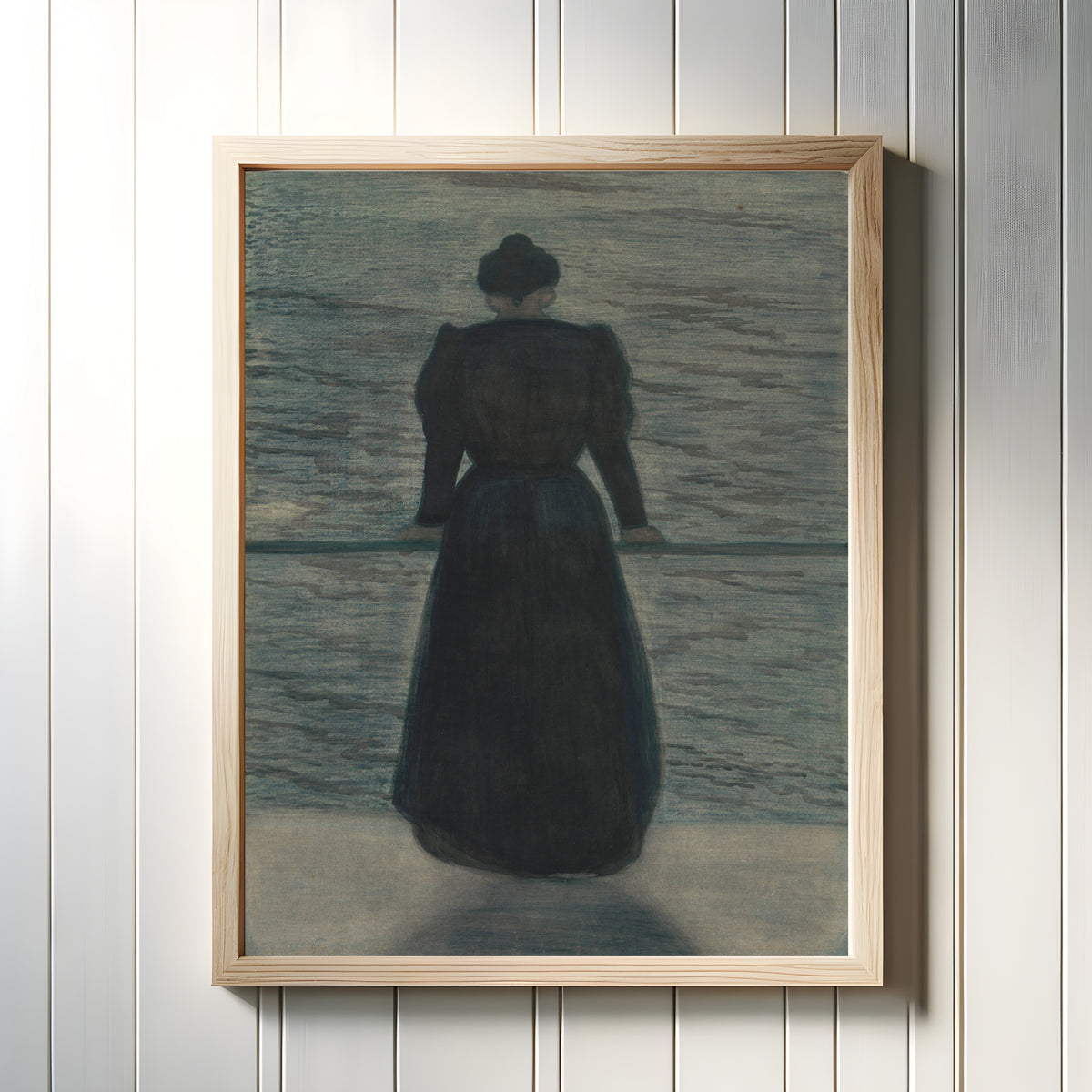 Framed art print of Woman by the Sea by Léon Spilliaert, in a light wood frame on a white panelled wall