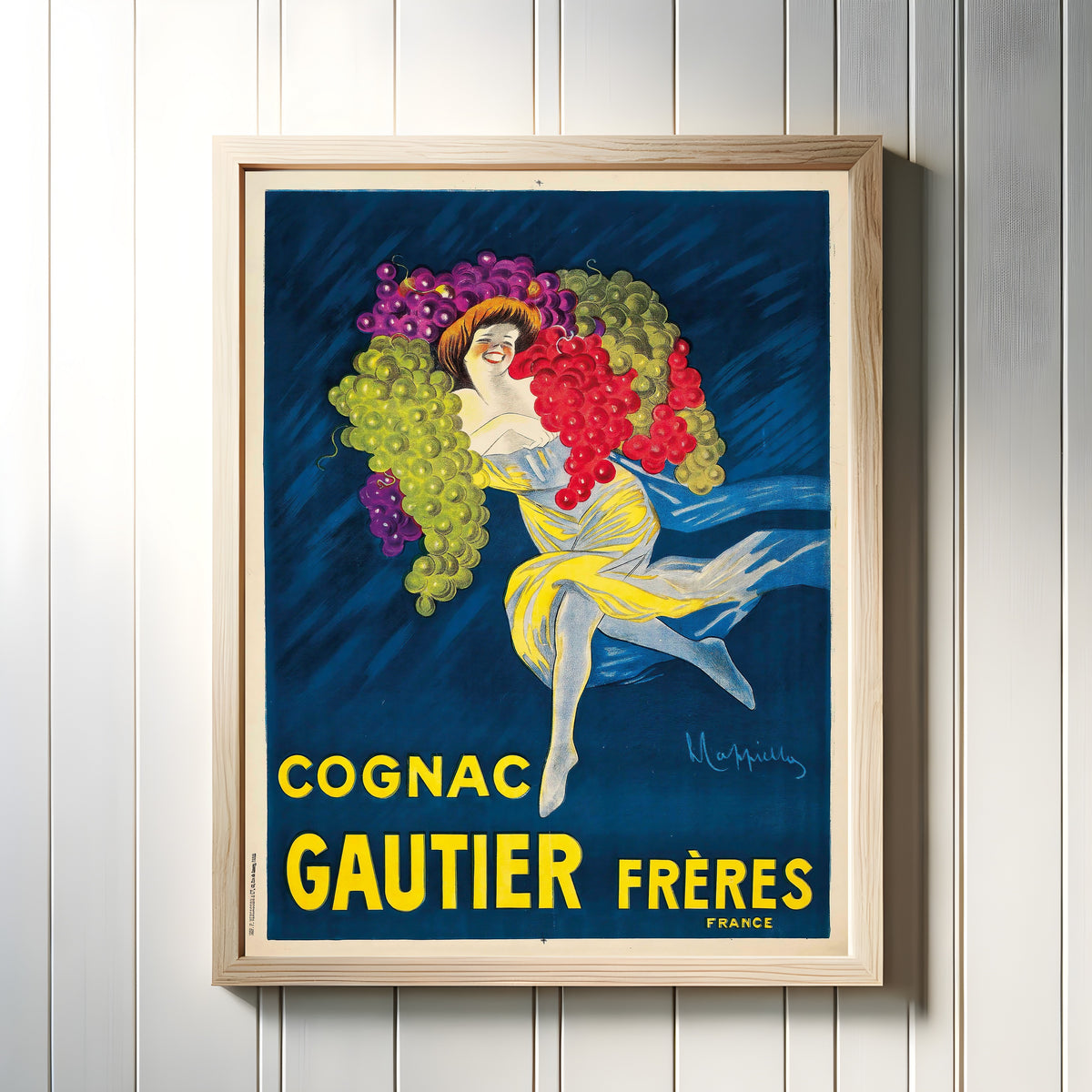 Framed art print of Cognac Gautier Frères by Leonetto Cappiello, in a light wood frame on a white panelled wall