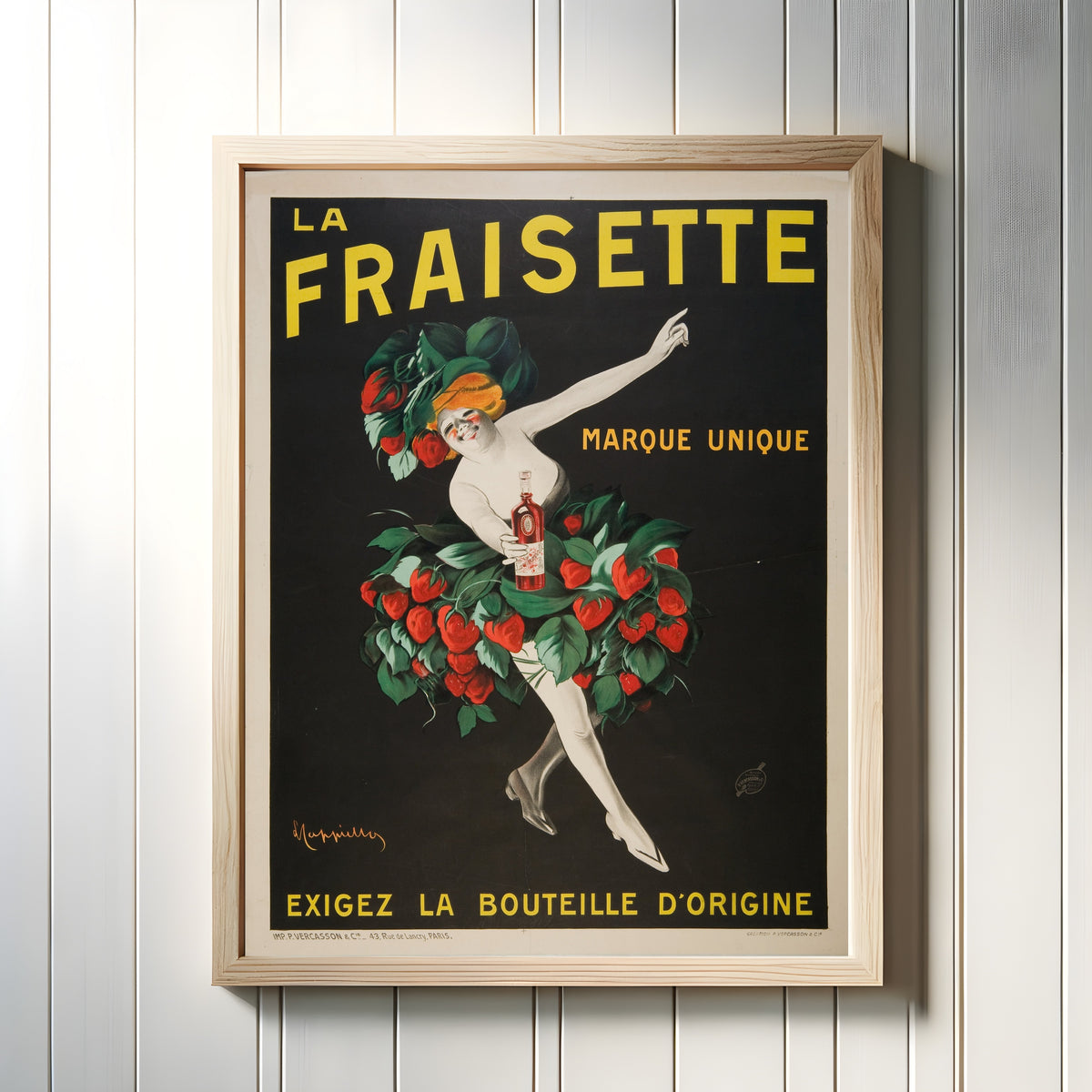 Framed art print of La Fraisette by Leonetto Cappiello, in a light wood frame on a white panelled wall