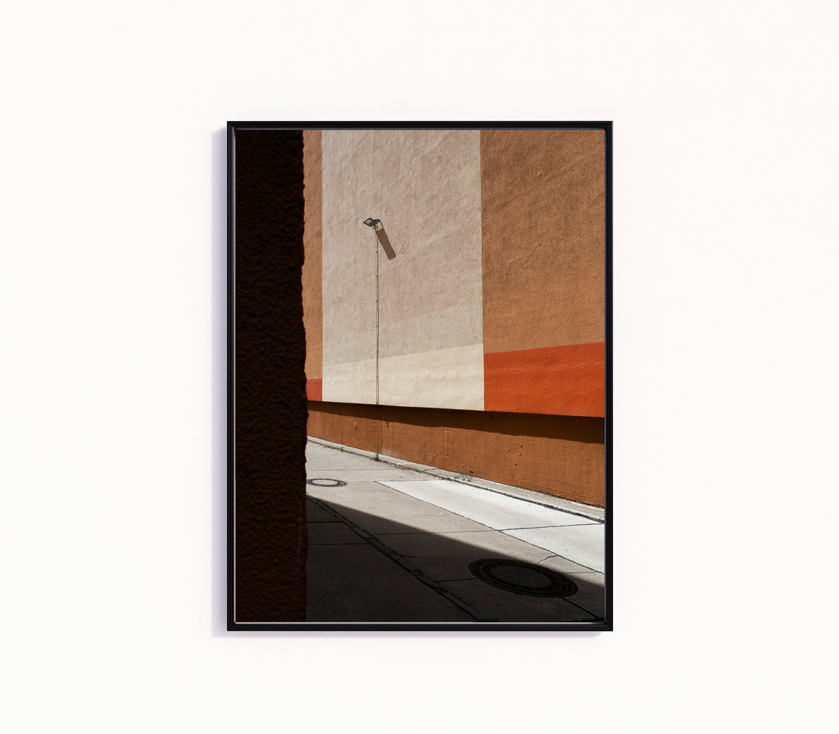 Framed art print of Light and Shadow I by Marcus Lenk, in a slim black frame on a plain white wall