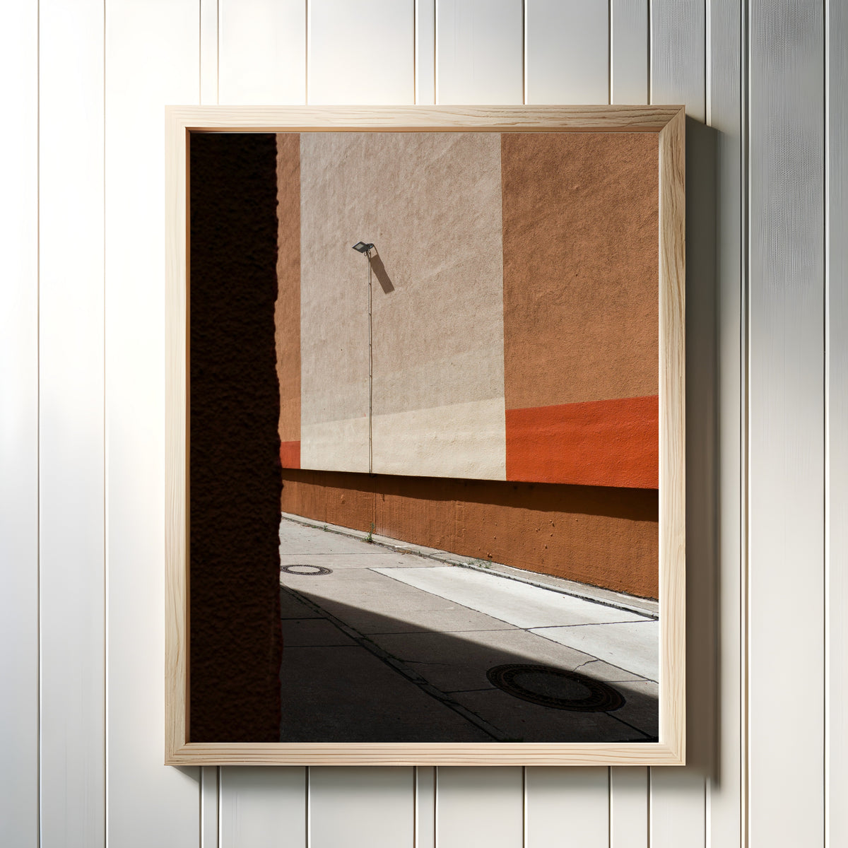 Framed art print of Light and Shadow I by Marcus Lenk, in a light wood frame on a white panelled wall