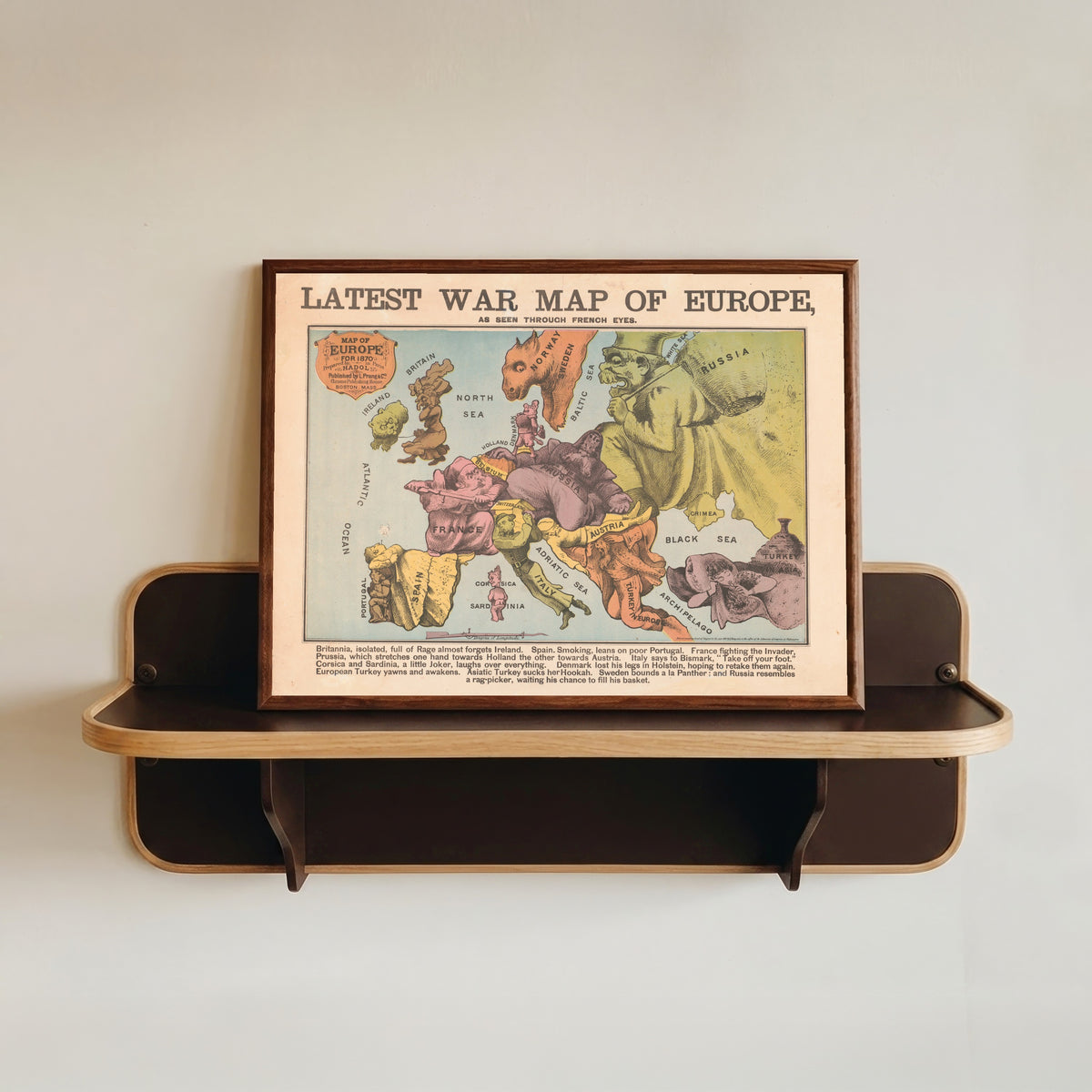 Framed art print of Latest War Map of Europe, as Seen Through French Eyes by Louis Prang & Co., in a dark wood frame resting on a wall shelf