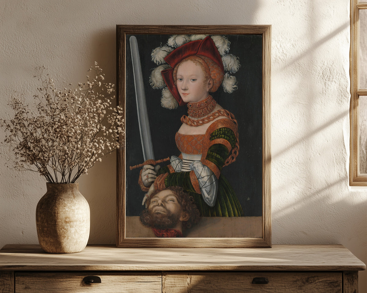 Framed art print of Judith with the Head of Holofernes by Lucas Cranach the Elder, in a dark wood frame leaning on a rustic console beside dried flowers