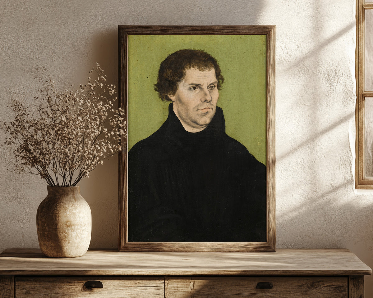 Framed art print of Martin Luther by Lucas Cranach the Elder, in a dark wood frame leaning on a rustic console beside dried flowers