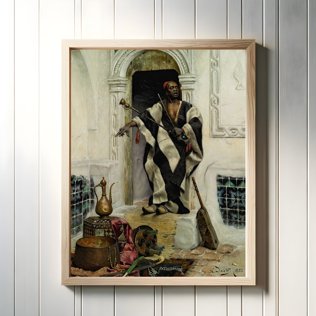 Framed art print of The Della'l by Ludwig Deutsch, in a light wood frame on a white panelled wall
