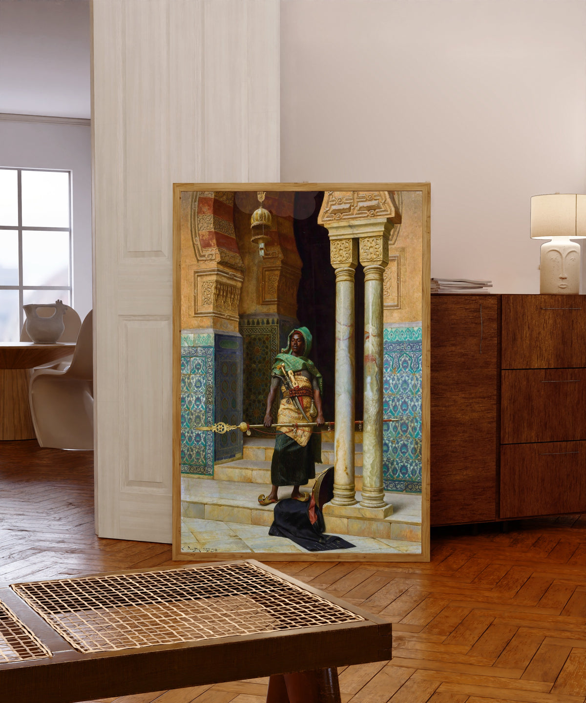 Framed art print of The Nubian Guard by Ludwig Deutsch, in a light wood frame leaning in a warm room with a parquet floor