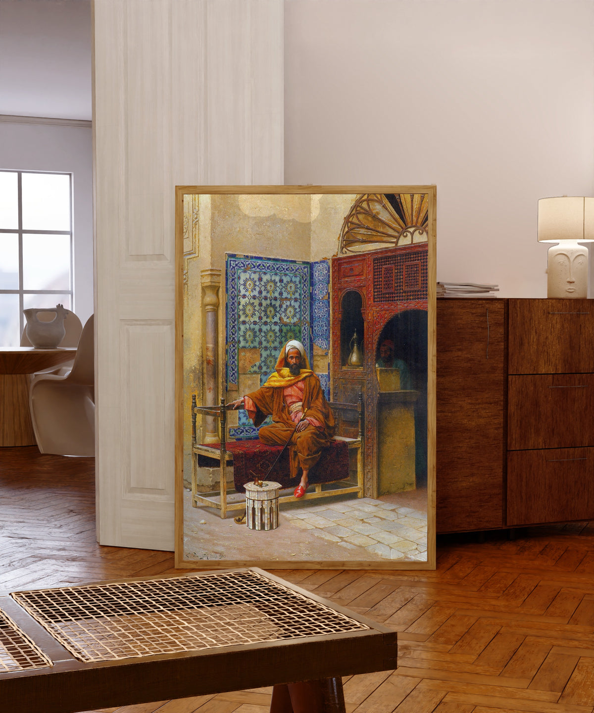 Framed art print of The Smoker by Ludwig Deutsch, in a light wood frame leaning in a warm room with a parquet floor