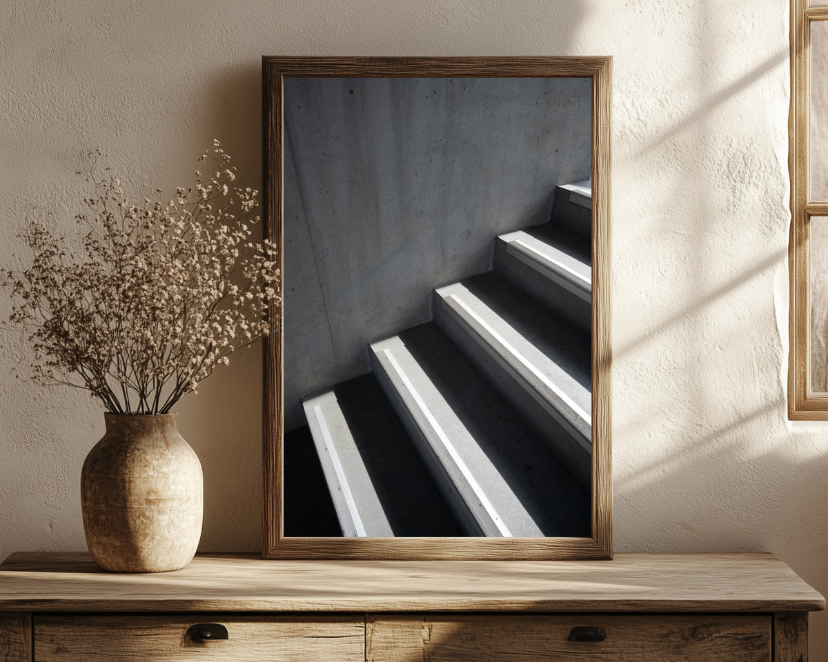 Framed art print of Light and Shadow VIII by Marcus Lenk, in a dark wood frame leaning on a rustic console beside dried flowers