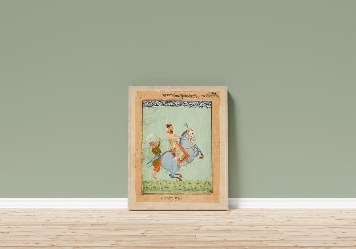 Framed art print of Prince Mathu Singh of Jatoli on a Blue Horse… by Mewar school, in a light wood frame leaning on a sage green wall above a wooden floor