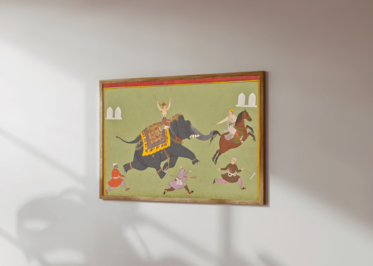 Framed art print of The Elephant of Maharana Jai Singh of Mewar Catches… by Mewar school, in a light wood frame on a sunlit white wall, seen at a slight angle