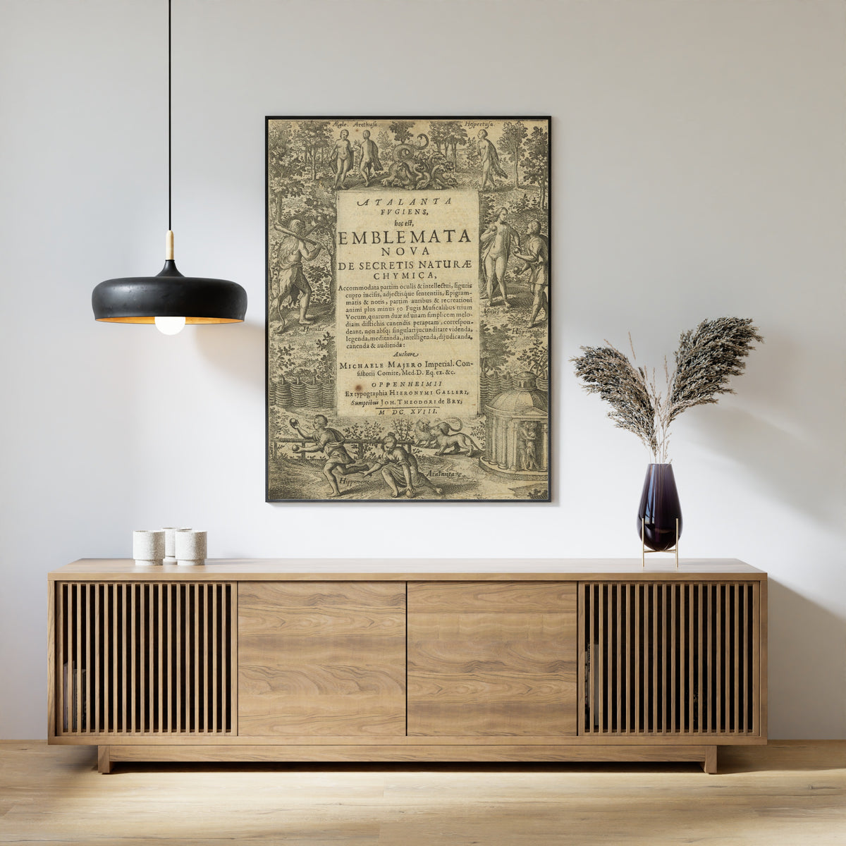 Framed art print of Atalanta Fugiens, Title Page by Michael Maier, above a slatted wood sideboard