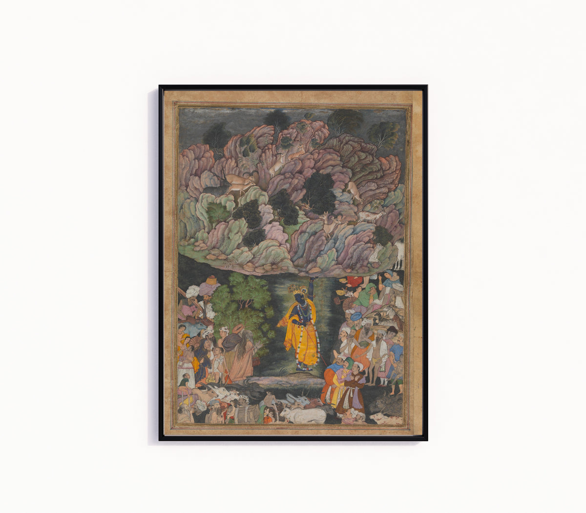 Framed art print of Krishna Holds Up Mount Govardhan to Shelter the Villagers of Braj, in a slim black frame on a plain white wall