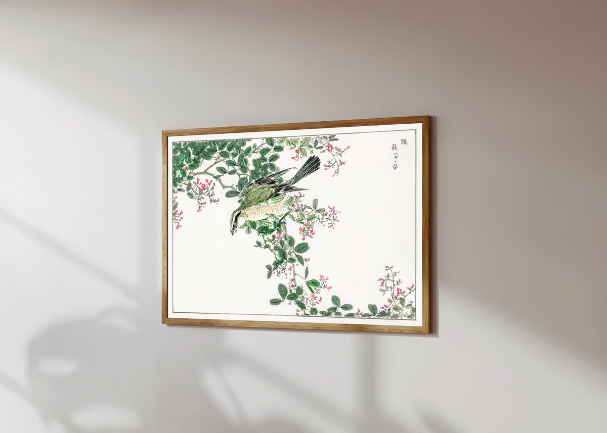 Framed art print of Bull-headed Shrike and Bush Clover by Numata Kashū, in a light wood frame on a sunlit white wall, seen at a slight angle