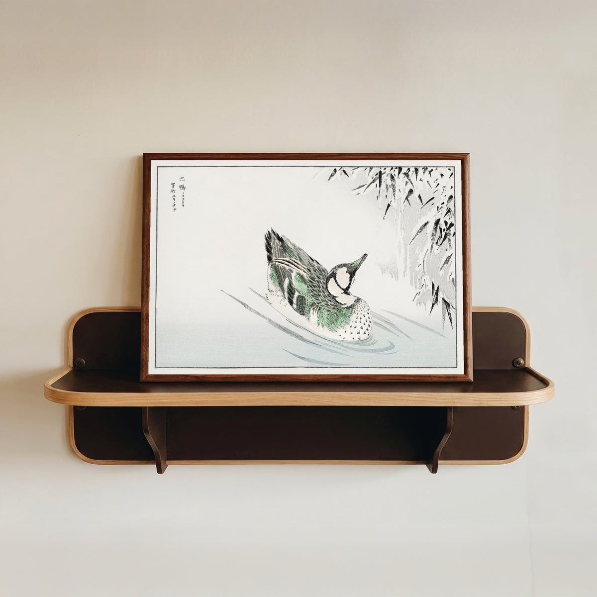 Framed art print of Spectacled Teal and Snow-bent Bamboo by Numata Kashū, in a dark wood frame resting on a wall shelf