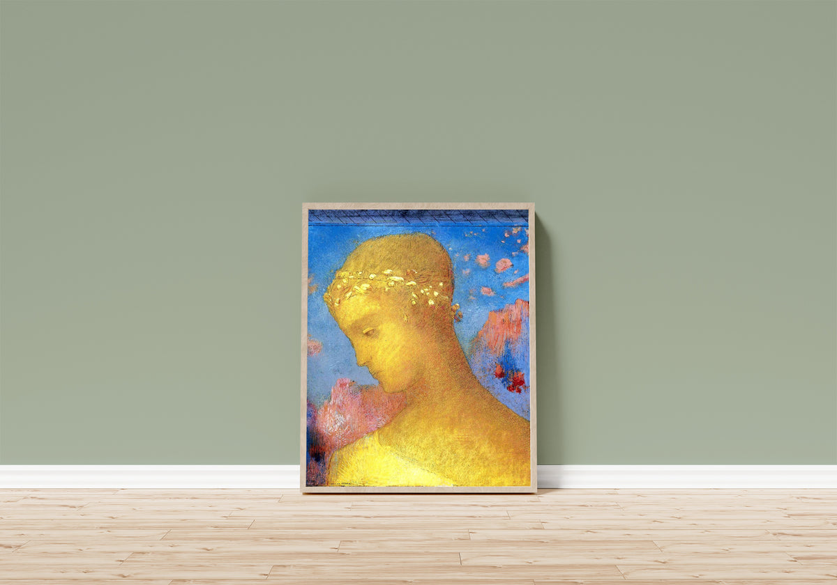Framed art print of Beatrice by Odilon Redon, in a light wood frame leaning on a sage green wall above a wooden floor