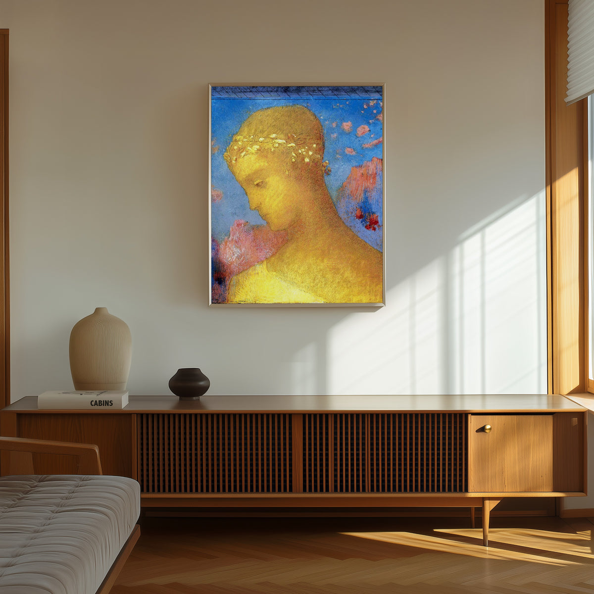 Framed art print of Beatrice by Odilon Redon, in a thin light frame on a sunlit wall above a wooden sideboard