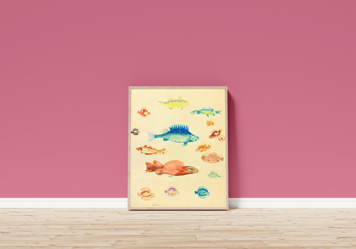 Framed art print of Fish by Odilon Redon, in a light wood frame leaning on a pink wall above a wooden floor
