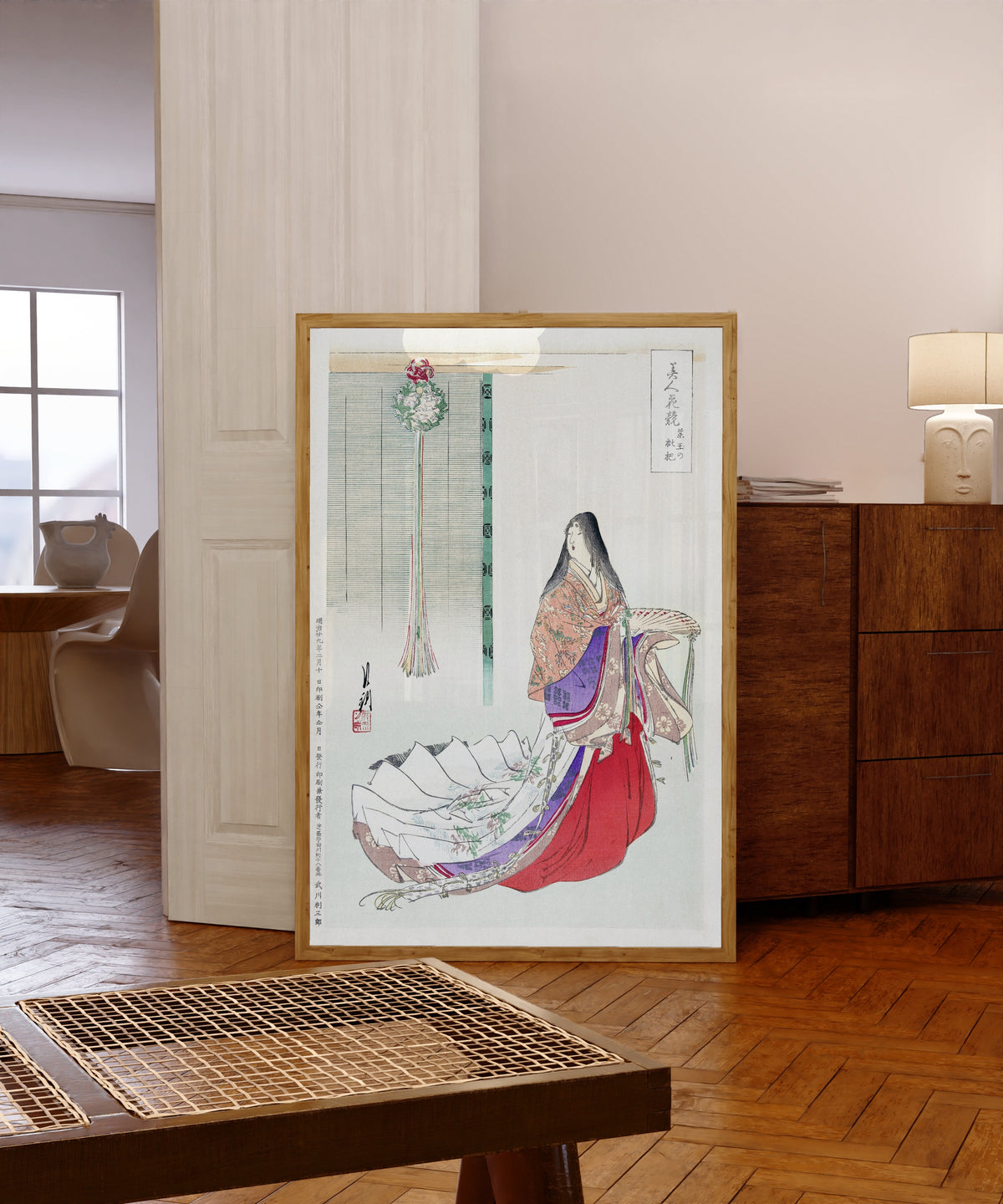 Framed art print of Heian Lady Waiting (1896) by Ogata Gekkō, in a light wood frame leaning in a warm room with a parquet floor