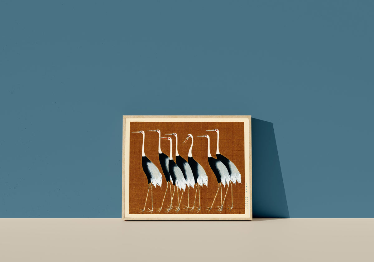 Framed art print of Cranes in Brown by Ogata Korin, in a light wood frame leaning on a blue wall